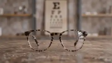 Brille vor unscharfer ferner Sehtafel — Symbol für Kurzsichtigkeit